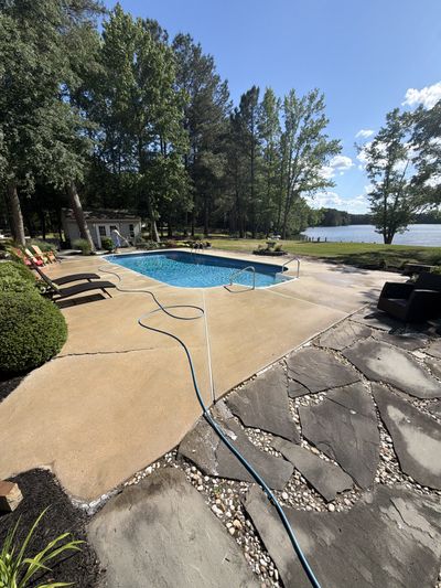 A pool deck being pressure washed, algae and grime lifting from the concrete