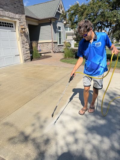 A Loukides Power Washing technician applying concrete sealer to a driveway
