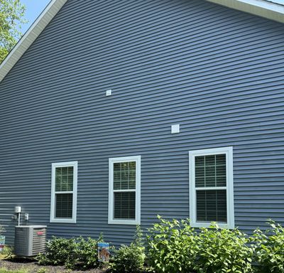 A freshly washed blue vinyl sided home with clean white trim