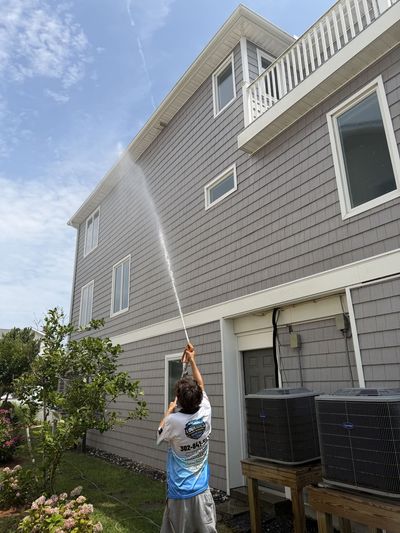 Our technician washing the siding of a large grey home