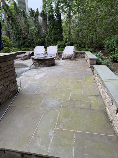 Flagstone patio covered in green moss before cleaning